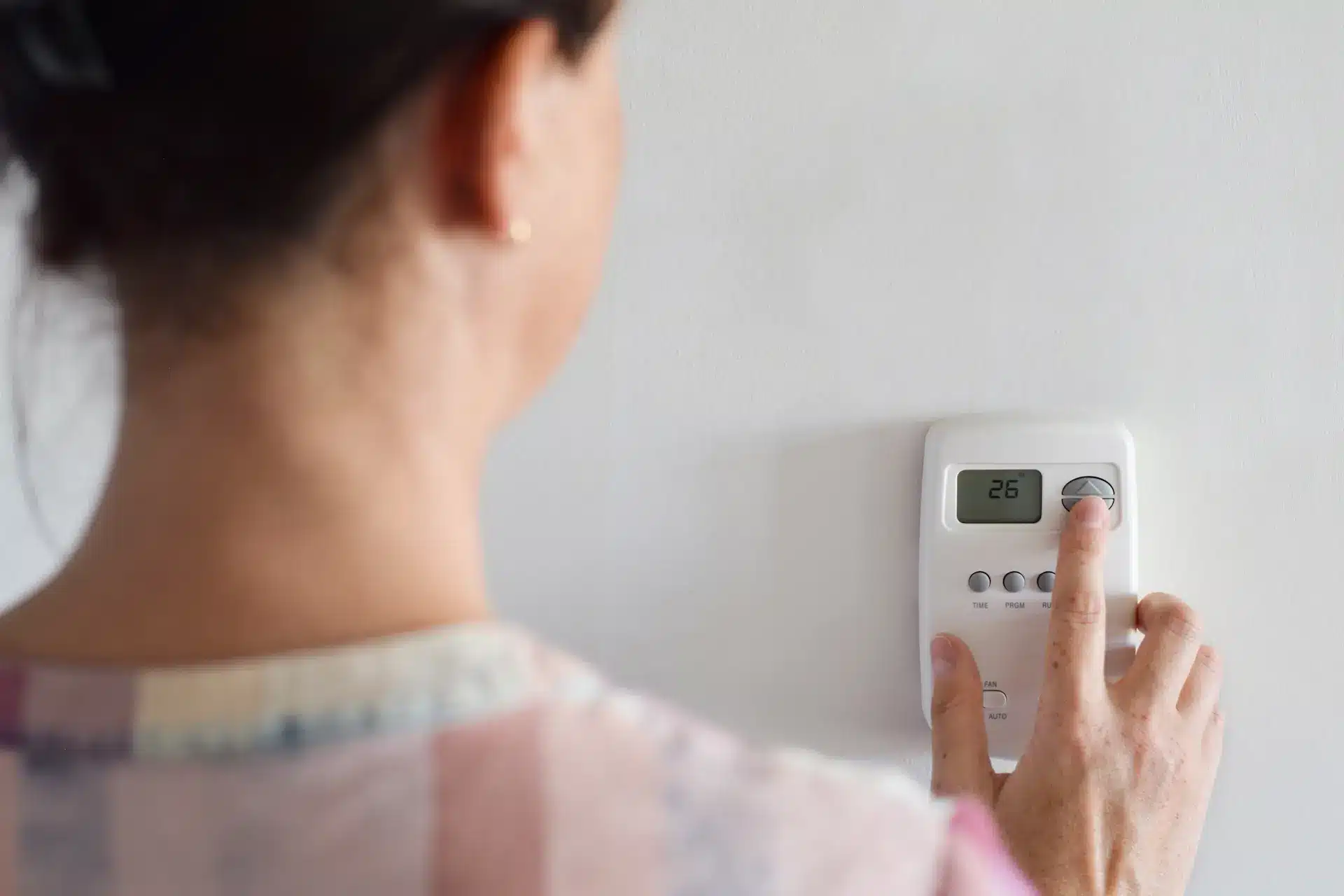 woman adjusting thermostat settings because furnace running constantly