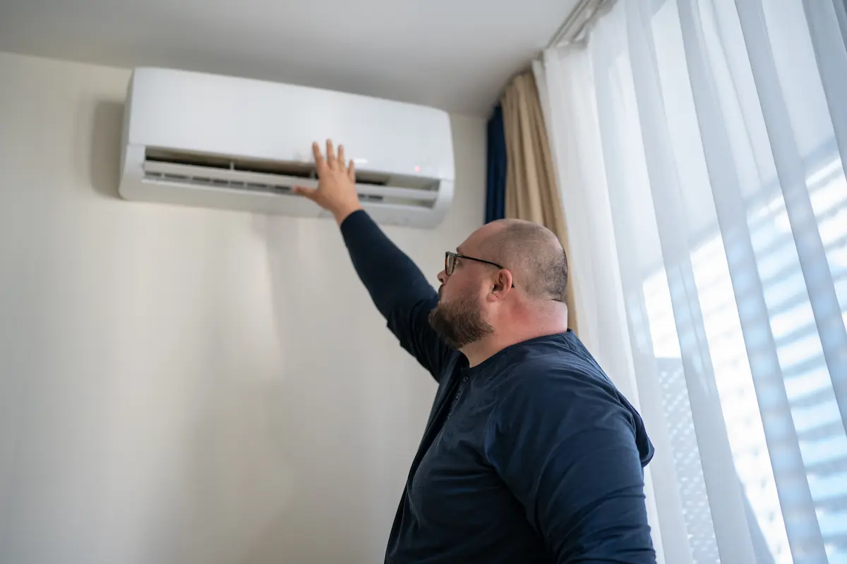 man checks air vent to see why his AC keeps turning off and on