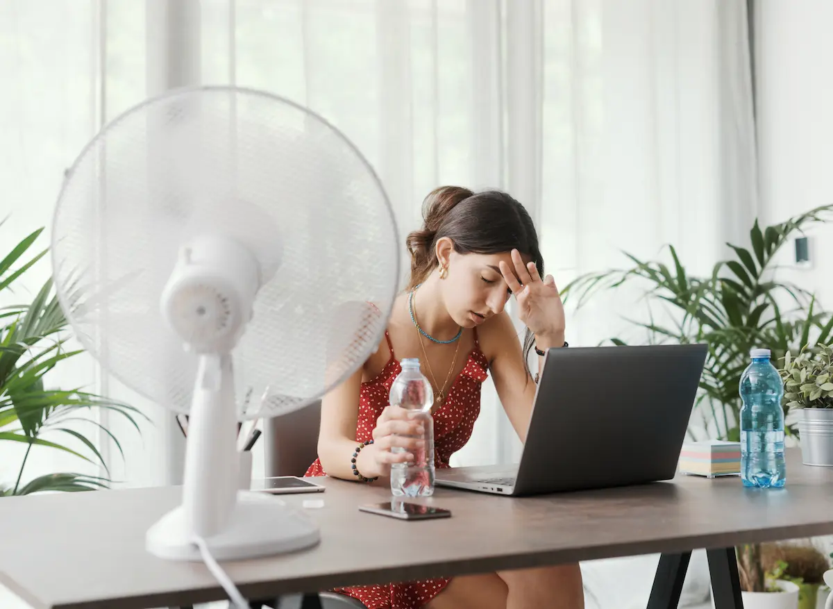 Woman cooling herself with an electric fan